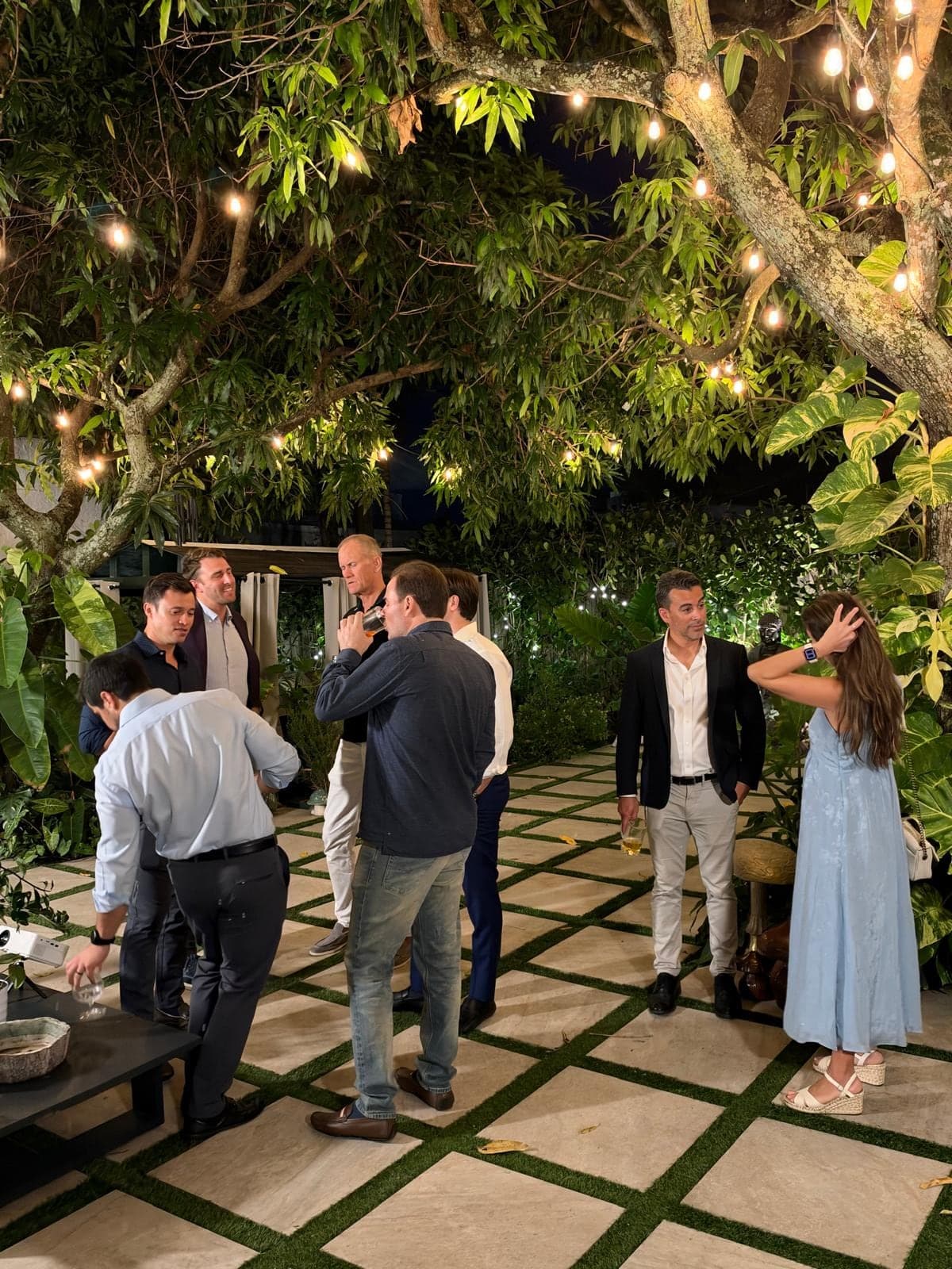 Guests talking under string lights at a Kontaktsource evening in a garden